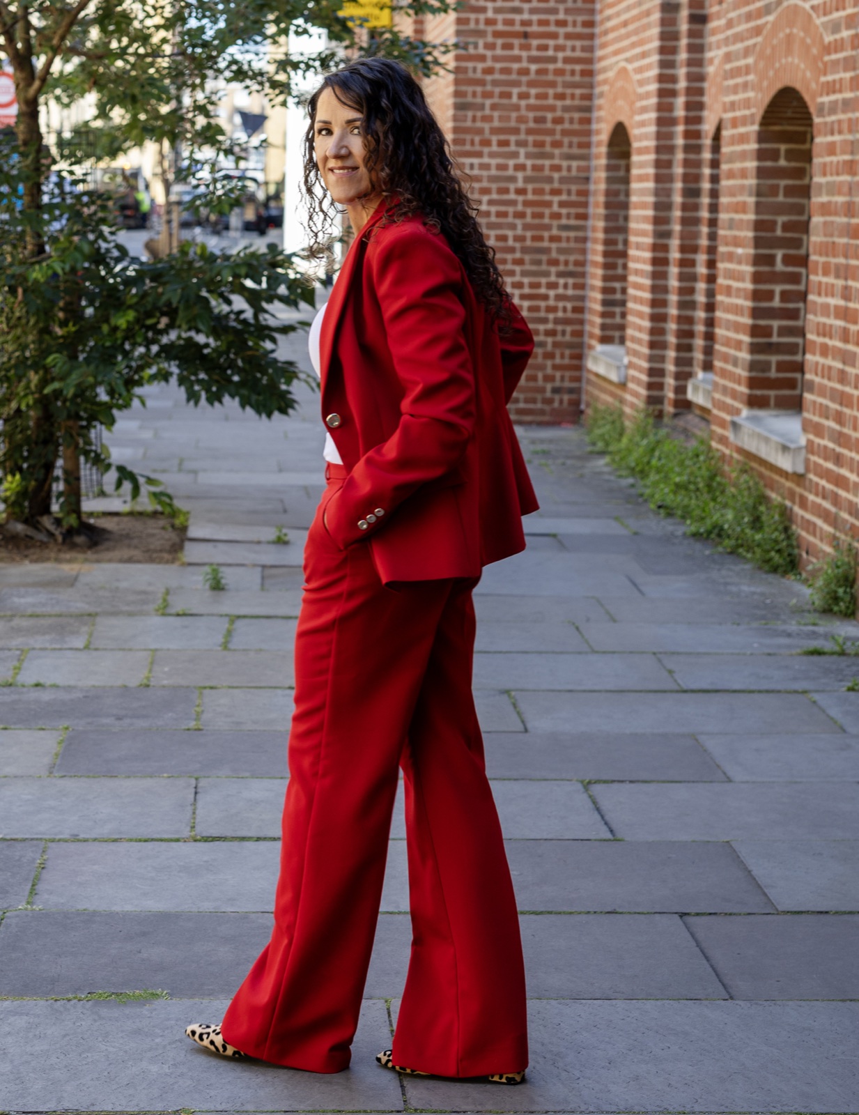 Polly Sheldon in a red suit, representing confident creative leadership through business transformation